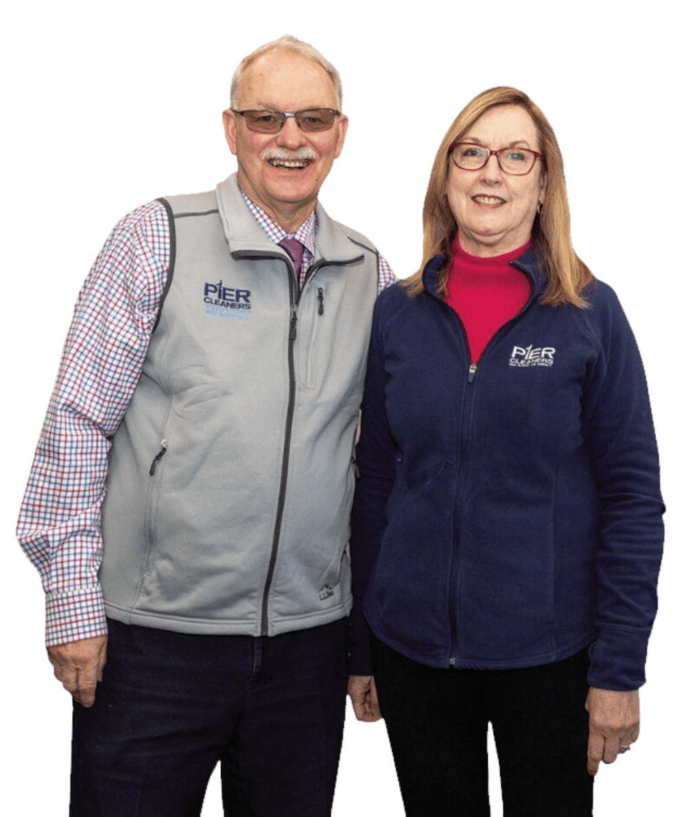 A man and woman stand side by side, both wearing jackets with