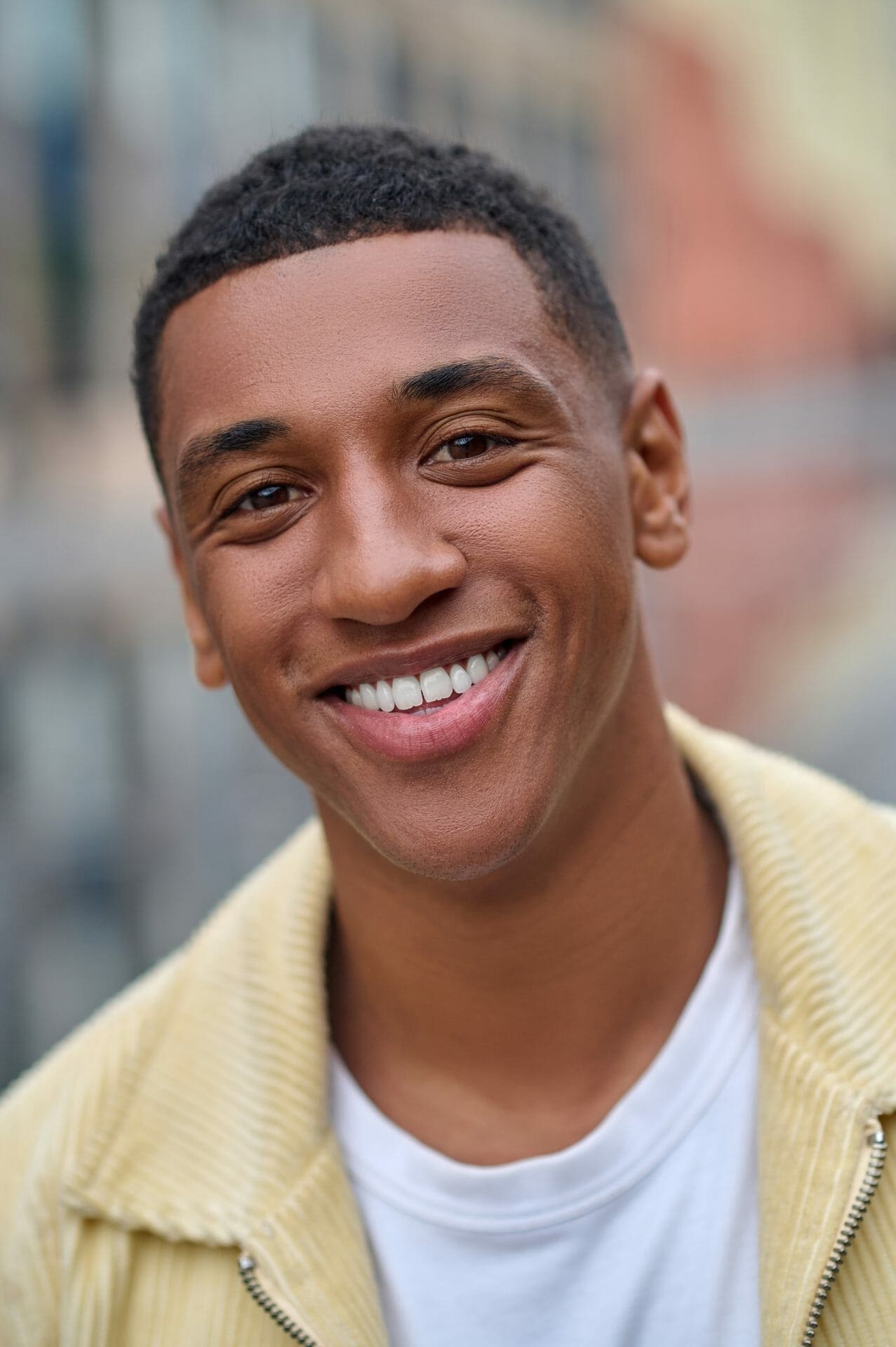 A smiling young man in a yellow jacket.