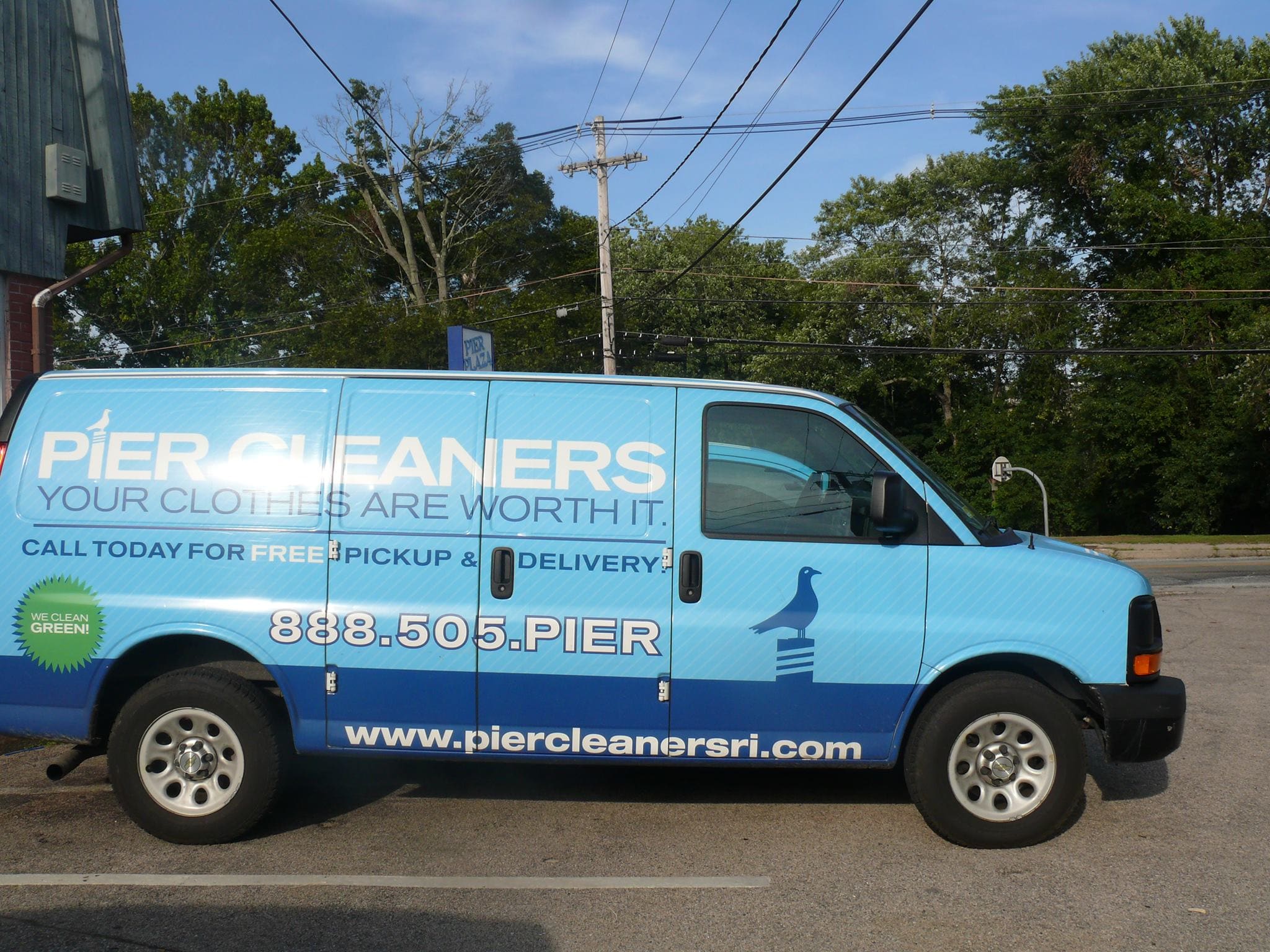 Blue Pier Cleaners van with company branding and contact details, parked in a lot near trees and power lines.