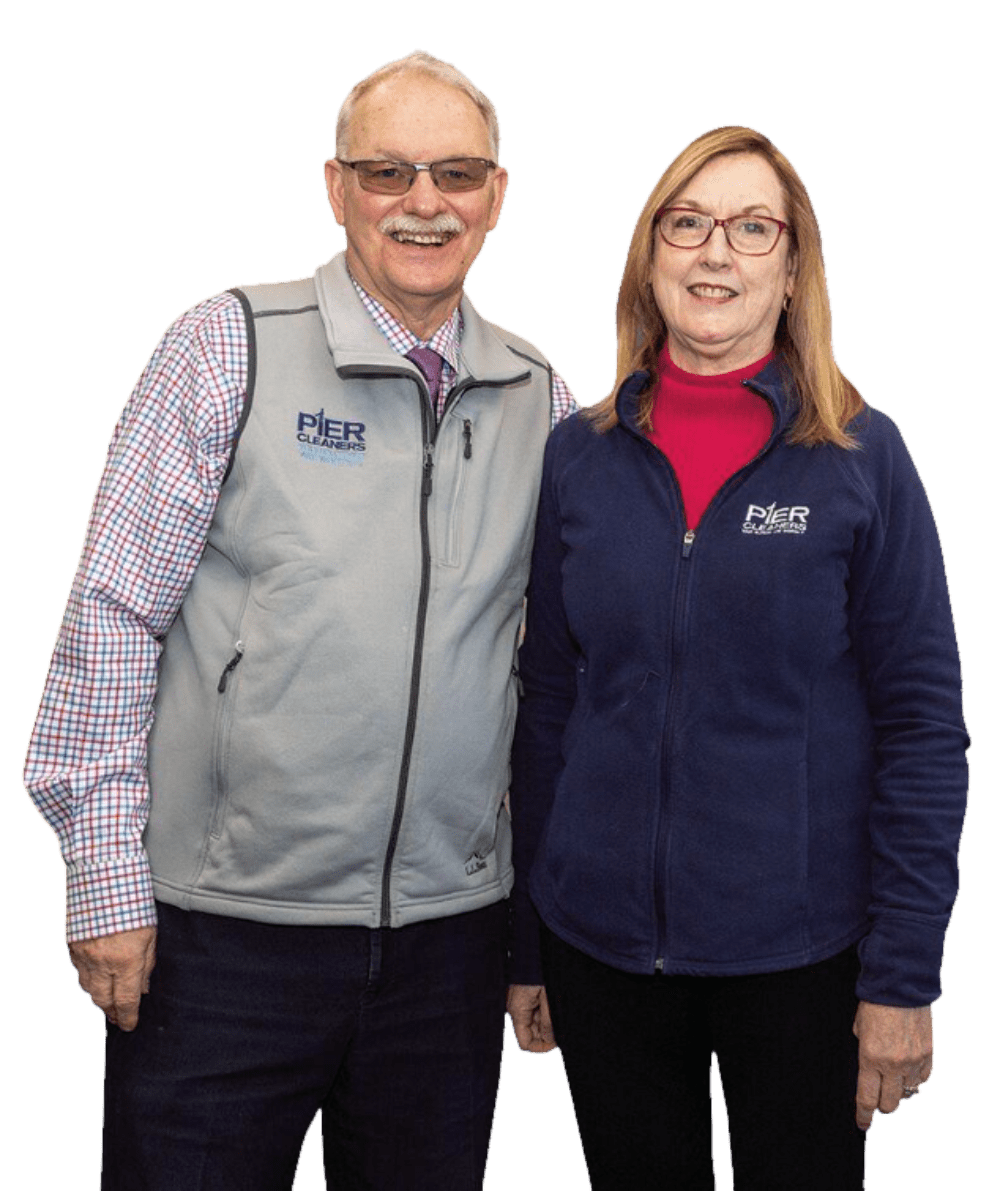 A man and woman stand side by side, both wearing jackets with